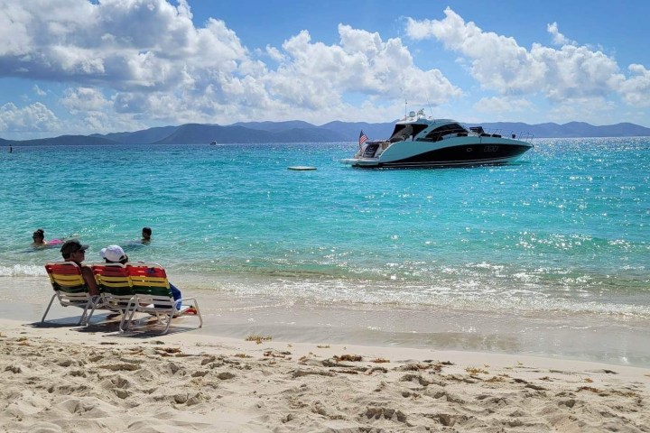 a man sitting on top of a sandy beach next to the ocean